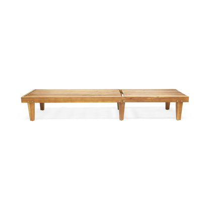 The Nadine Stylish Chaise Lounge Chair in teak features a simple rectangular design with six legs and a slatted seat, shown against a plain white background.