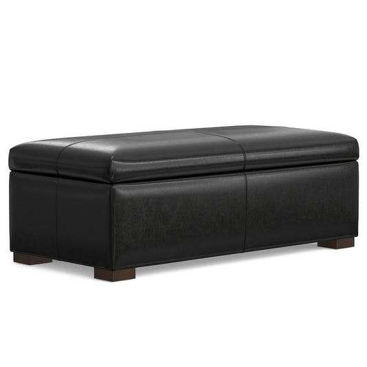 The Gabbie - Coffee Table Upholstered Storage Ottoman is a rectangular black leather piece with a cushioned top and short wooden legs, serving as a seat, footrest, or storage bench.
