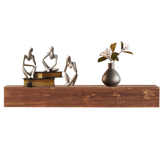 The Rustic Wood Fireplace Mantel, a wall-mounted floating shelf, elegantly displays three abstract figurines, stacked books, a pinecone, and a gray vase with white flowers and greenery.