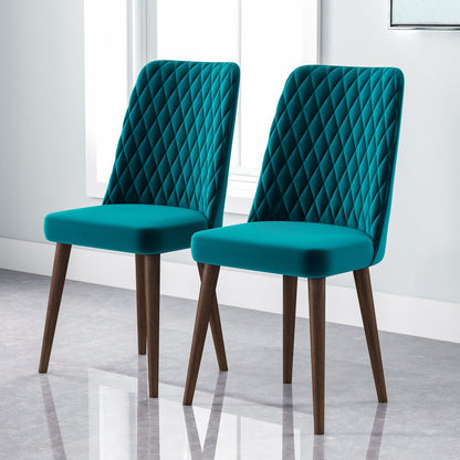 A set of two Katie Mid-Century Modern Dining Chairs with diamond-patterned teal upholstery and wooden legs sit side by side in a bright, minimalist room featuring large windows and a light gray floor.