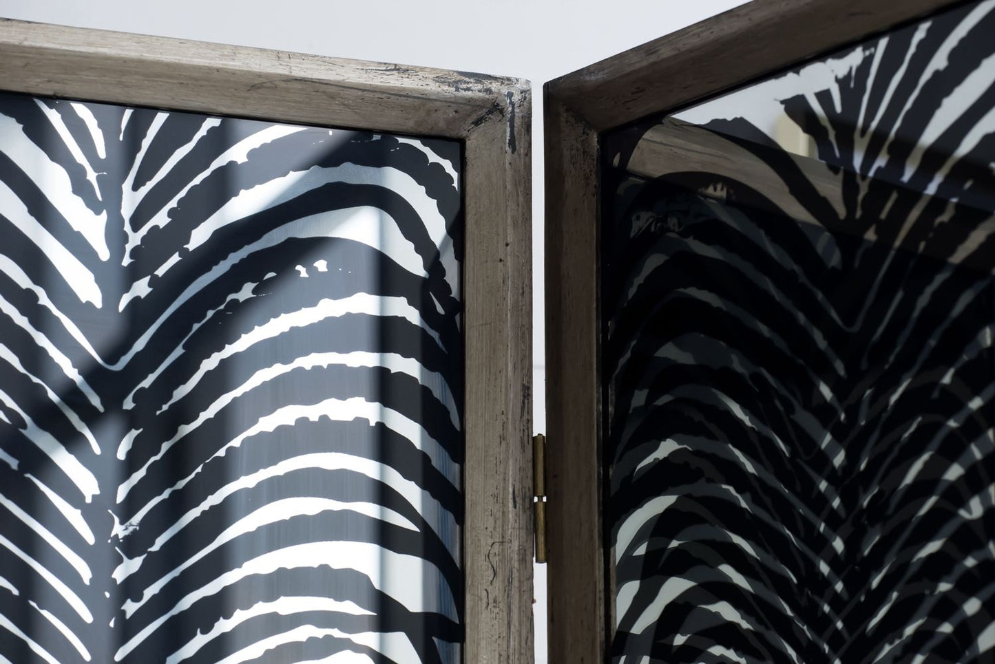 Close-up of the Room Divider, Herero 4 Panel Decorative Screen - Black, showcasing a black and white abstract zebra stripe pattern on glass with a wooden frame. The partially open divider beautifully reflects the pattern on its surface.