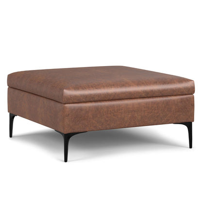 The Rebecca is a square, brown leather storage ottoman with a cushioned top, black metal legs, and a lift-up lid, shown against a white background.