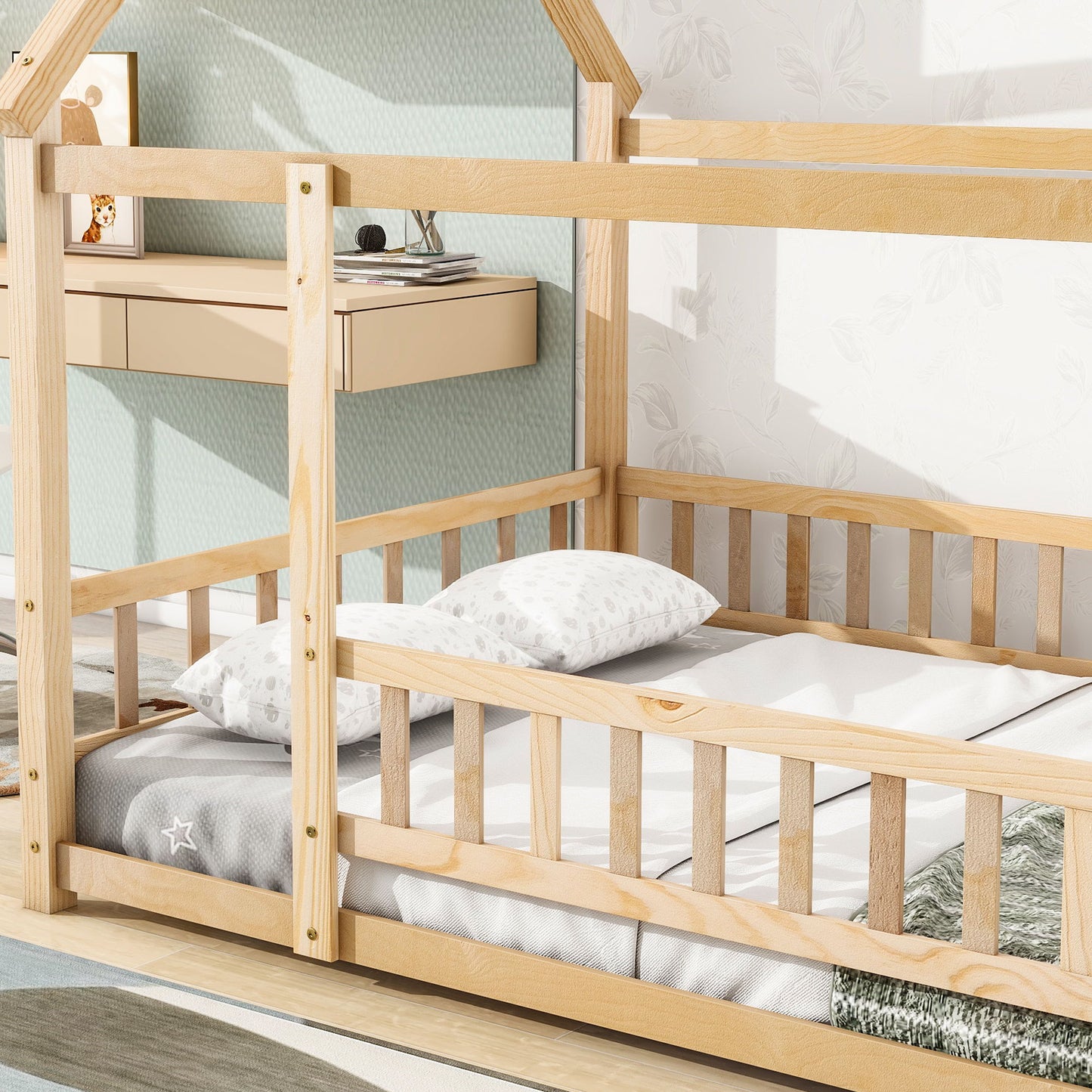 The Floor Wooden Bed With House Roof Frame and Fence Guardrails sits on a light wood floor, dressed in white and grey star bedding, next to a wall with light wallpaper and a floating beige drawer.