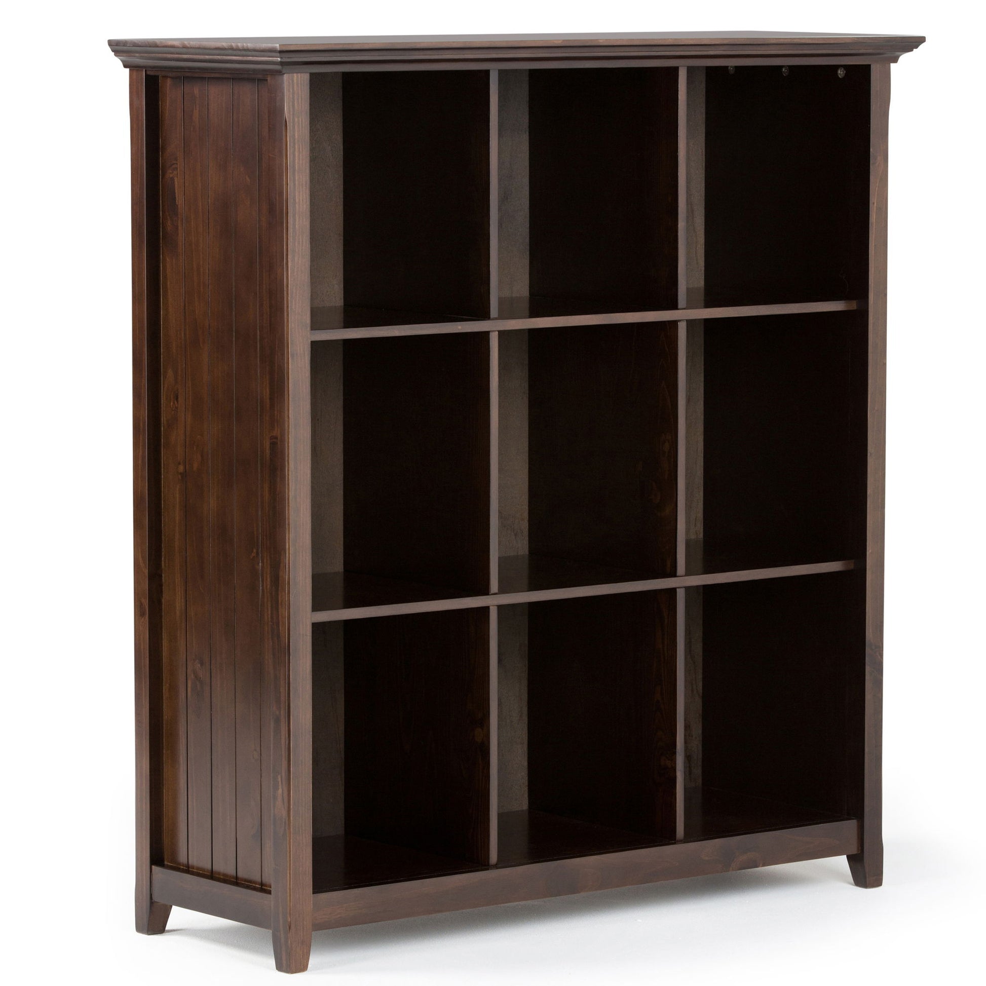 The Acadian - Handcrafted Cube Storage is a dark wooden bookcase with three shelves forming nine open square compartments, standing on four short legs and featuring vertical panel detailing on the back and sides.