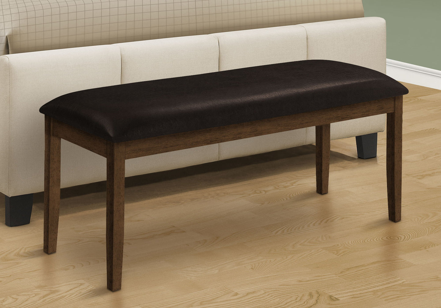 A rectangular upholstered hallway bench with four legs sits on a light wood floor in front of a cream sofa featuring a checkered backrest.