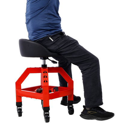 A person sits on a Pneumatic 360 Degree Swivel Stool, a heavy duty mechanics rolling creeper seat with black casters. Only their lower half is visible, wearing black pants, black shoes, and a blue shirt.