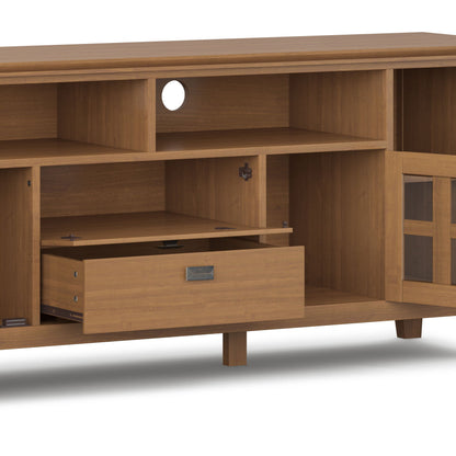 The Artisan - TV Media Stand features multiple shelves, one open drawer, a right-side glass door, and a circular cable management hole at the back. It stands elevated on four legs.