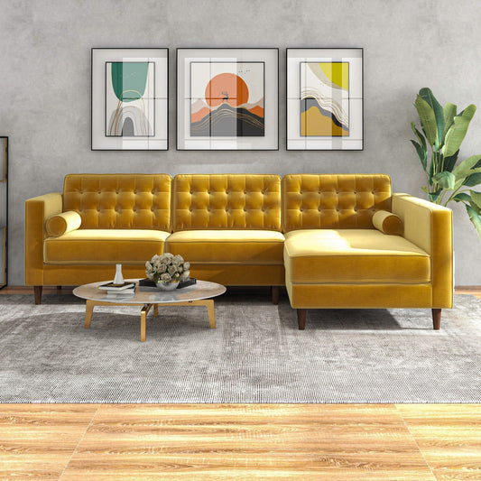 A modern living room featuring the Christian Mid-Century Modern Design Sectional Sofa in yellow, a round wooden coffee table with flowers, three abstract wall art pieces, a potted plant, and a gray rug over wood flooring.