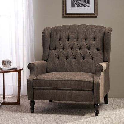The Dunham Contemporary Fabric Tufted Oversized Pushback Recliner with rolled arms sits on a carpeted floor beside a round wooden side table and a window with sheer white curtains, under a framed black-and-white photo on the beige wall.