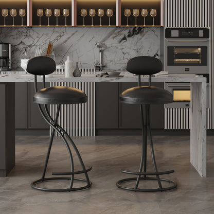 Two modern PU leather bar stools with footrests stand at a marble kitchen island. Behind them are shelves with wine glasses, a coffee maker, and built-in ovens set against a marble backsplash.