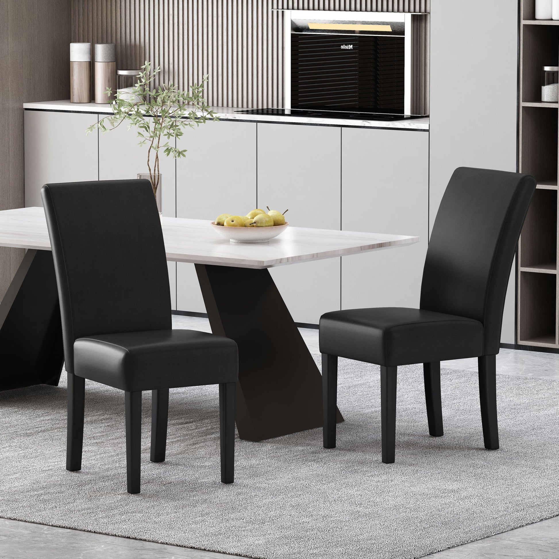 A set of two Contemporary Dining Chairs With Rubberwood Legs in black sits by a light rectangular dining table topped with fruit and a plant. The room features a gray rug, minimalist cabinets, and a built-in oven in the background.