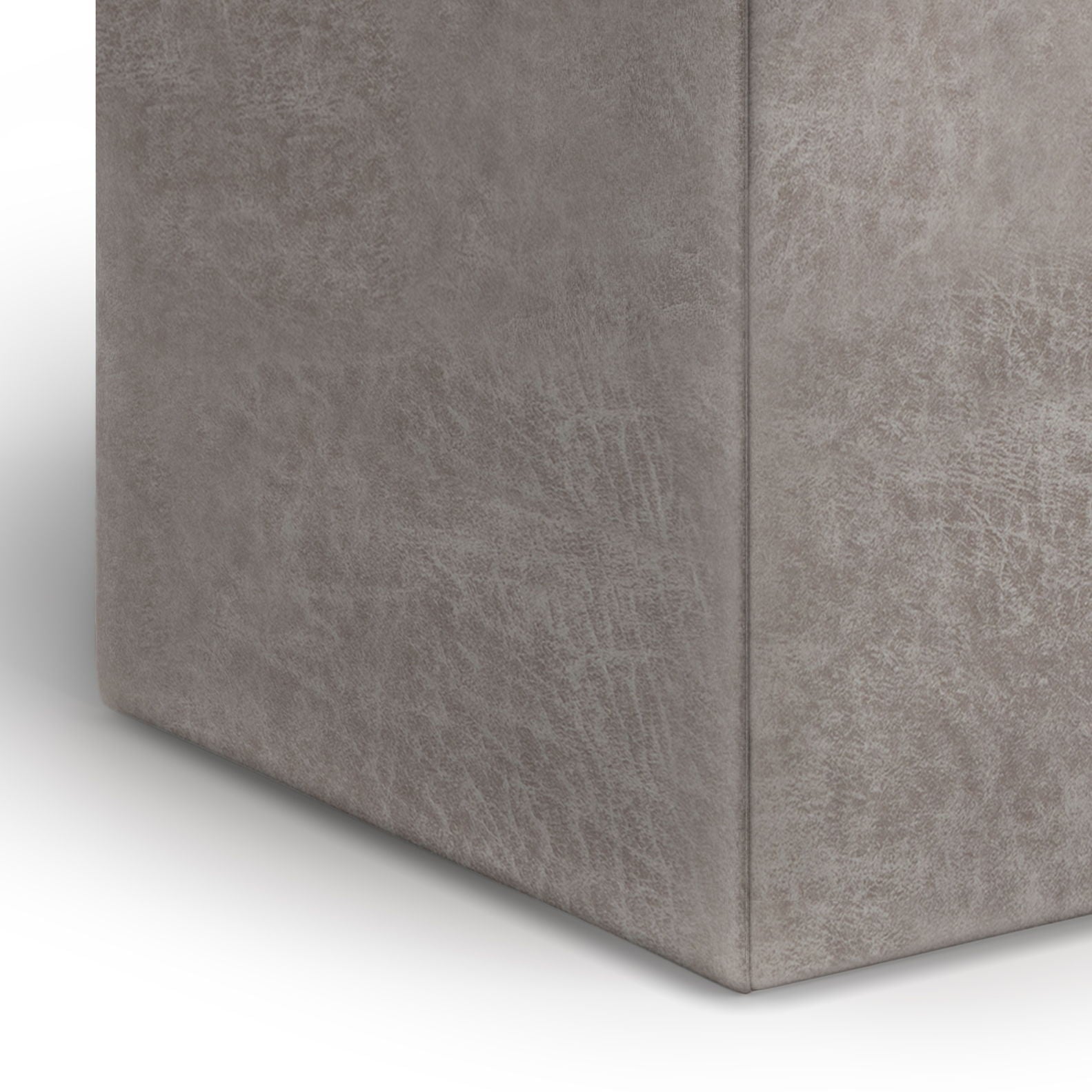 Close-up of the corner of the Rockwood - Upholstered Cube Storage Ottoman With Tray, showing its grey, rectangular form and soft, textured upholstered surface against a white background.