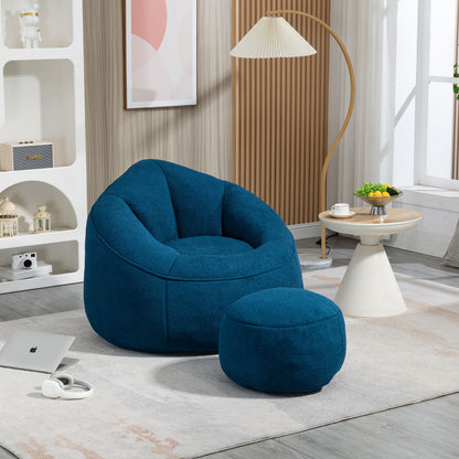 A modern living room featuring the Bedding Bean Bag Sofa Chair High Pressure Foam With Footrest on a light rug, a round side table with fruit and a teacup, plus a laptop and headphones on the floor in soft natural light.