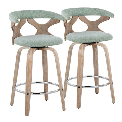 The Gardenia Mid Century Modern Fixed Height Counter Stools (Set of 2) feature light wood legs, chrome footrests, curved backs with cut-out designs, and seats upholstered in light green fabric. Swivel function included.