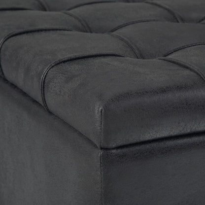 Close-up of the Harrison Upholstered Coffee Table Storage Ottoman in black, featuring a tufted faux leather surface with stitched square patterns on the cushioned top corner.