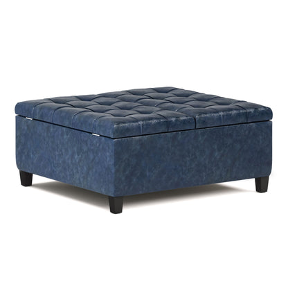 The Harrison Upholstered Coffee Table Storage Ottoman is a square, dark blue piece with short black legs and leather-like upholstery. Its cushioned top has a grid pattern and button tufting for added style.