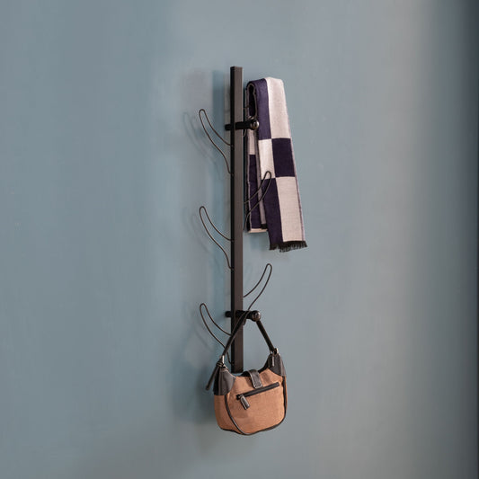 A Vertical Eight Hook Coat Rack Wall Mount in black holds a checkered scarf and a tan handbag against a plain blue wall.