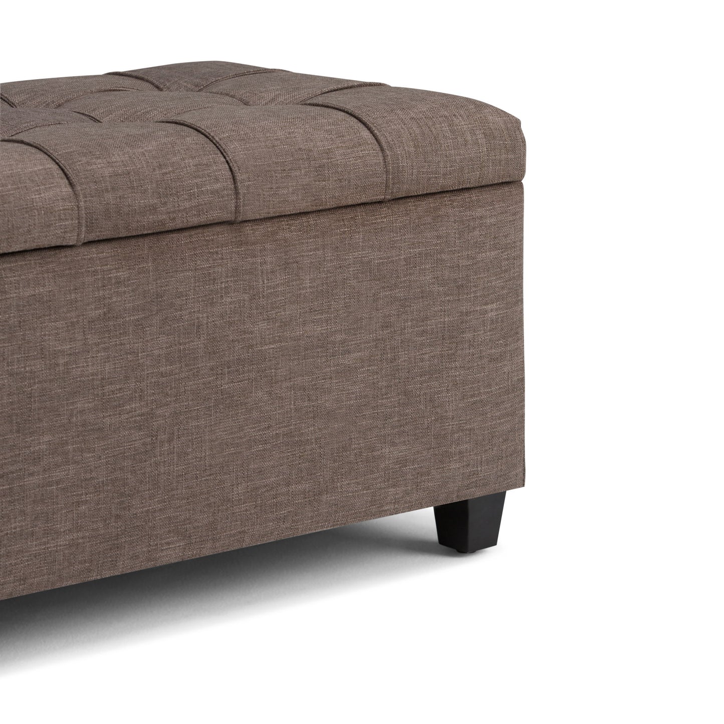 A close-up of the Sienna Upholstered Storage Ottoman Bench featuring brown fabric, a tufted cushioned lid, and short black legs, shown against a white background.