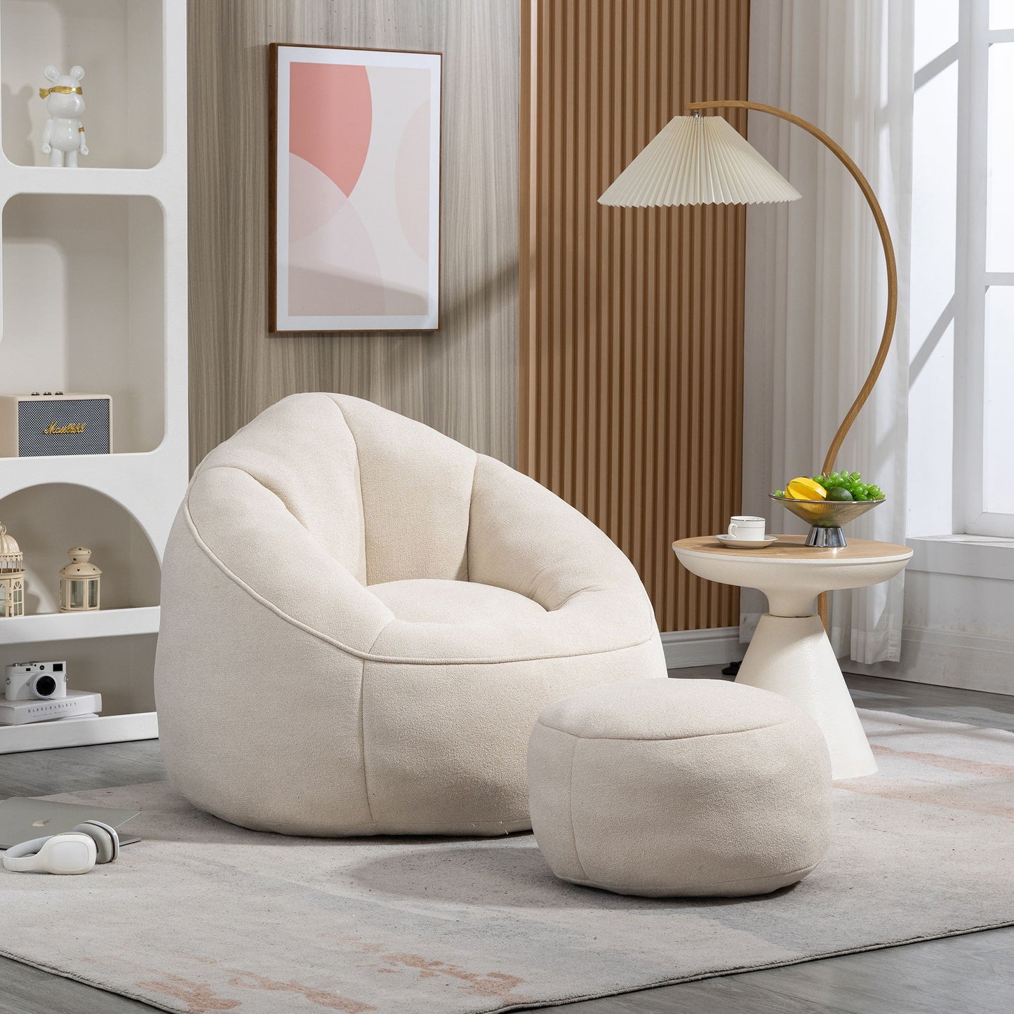 The Bedding Bean Bag Sofa Chair High Pressure Foam With Footrest, in cream, sits on a light gray rug in a modern living room by a round side table and floor lamp, illuminated by natural light from a window.