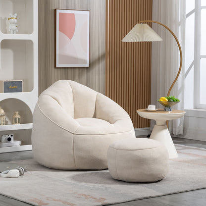 The Bedding Bean Bag Sofa Chair High Pressure Foam With Footrest, in cream, sits on a light gray rug in a modern living room by a round side table and floor lamp, illuminated by natural light from a window.
