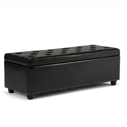 The Hamilton Upholstered Storage Ottoman features a rectangular black leather design with a tufted top, low wooden legs, and brass nailhead trim along the bottom edge.