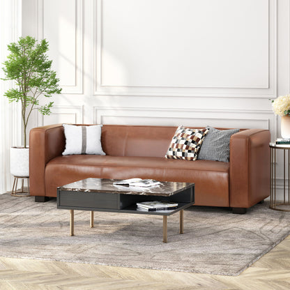 A modern living room featuring the Contemporary 3 Seater Sofa With Tuxedo Design in brown leather, two patterned cushions, a black marble coffee table, a potted plant, and a light rug on wooden floors with white paneled walls in the background.