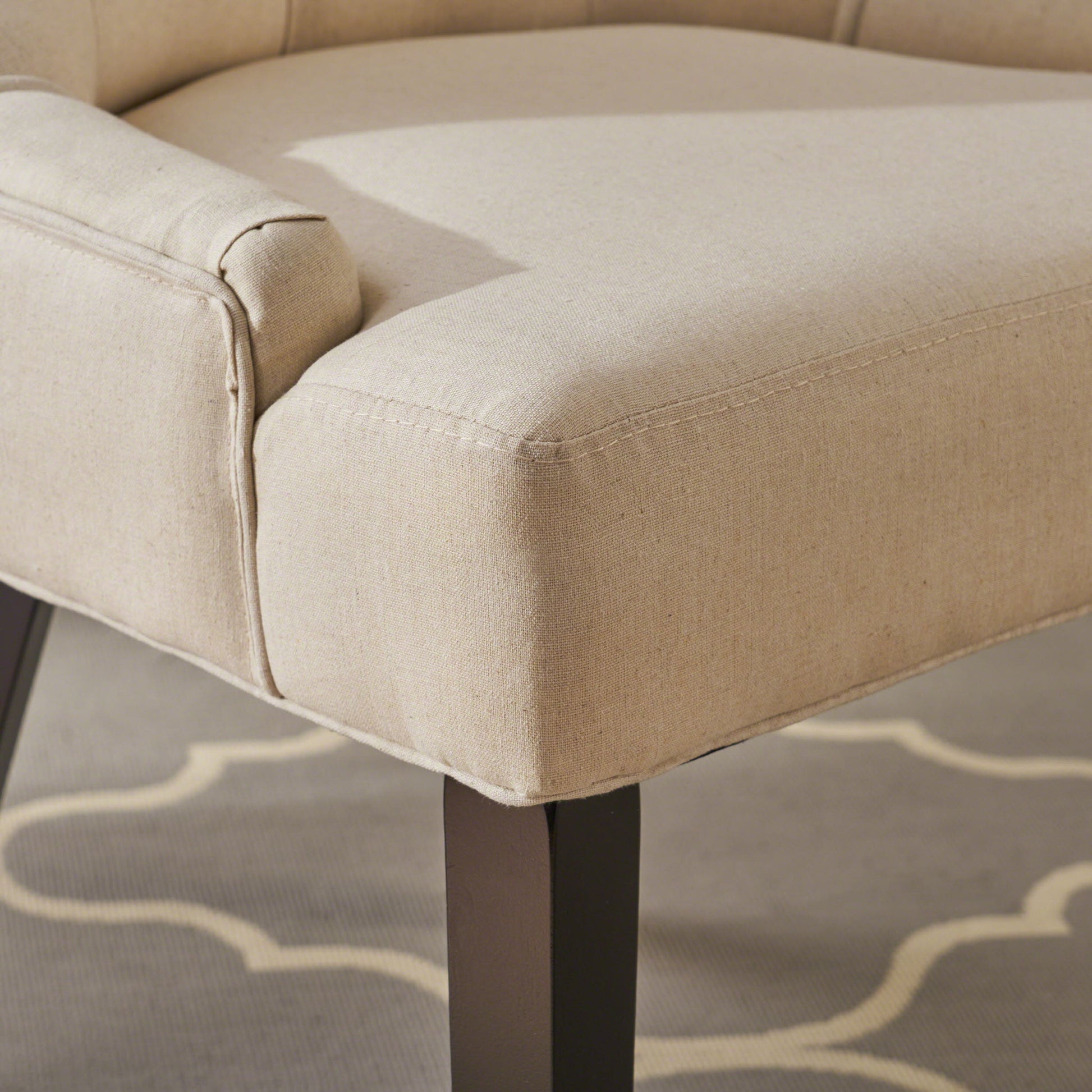 Close-up of the Cheney Contemporary Dining Chair set, featuring beige tufted upholstery and dark wooden legs, displayed on a gray rug with a white geometric pattern.