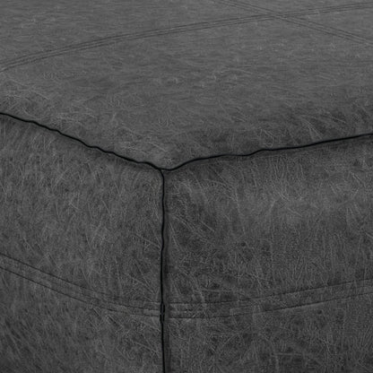 Close-up of the Brody - Large Square Coffee Table Pouf in dark grey leather, highlighting its corner with visible stitching and textured surface detail.