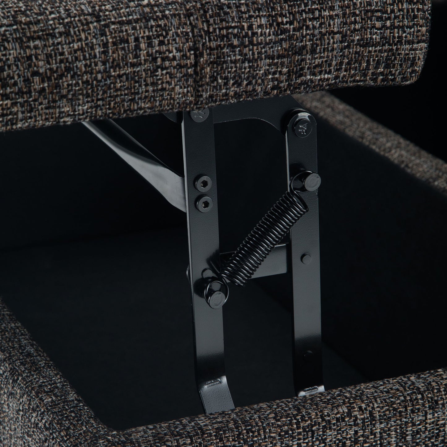 Close-up of a metal hinge and spring mechanism inside the Harrison Upholstered Coffee Table Storage Ottoman, with its fabric-covered lid partially open.