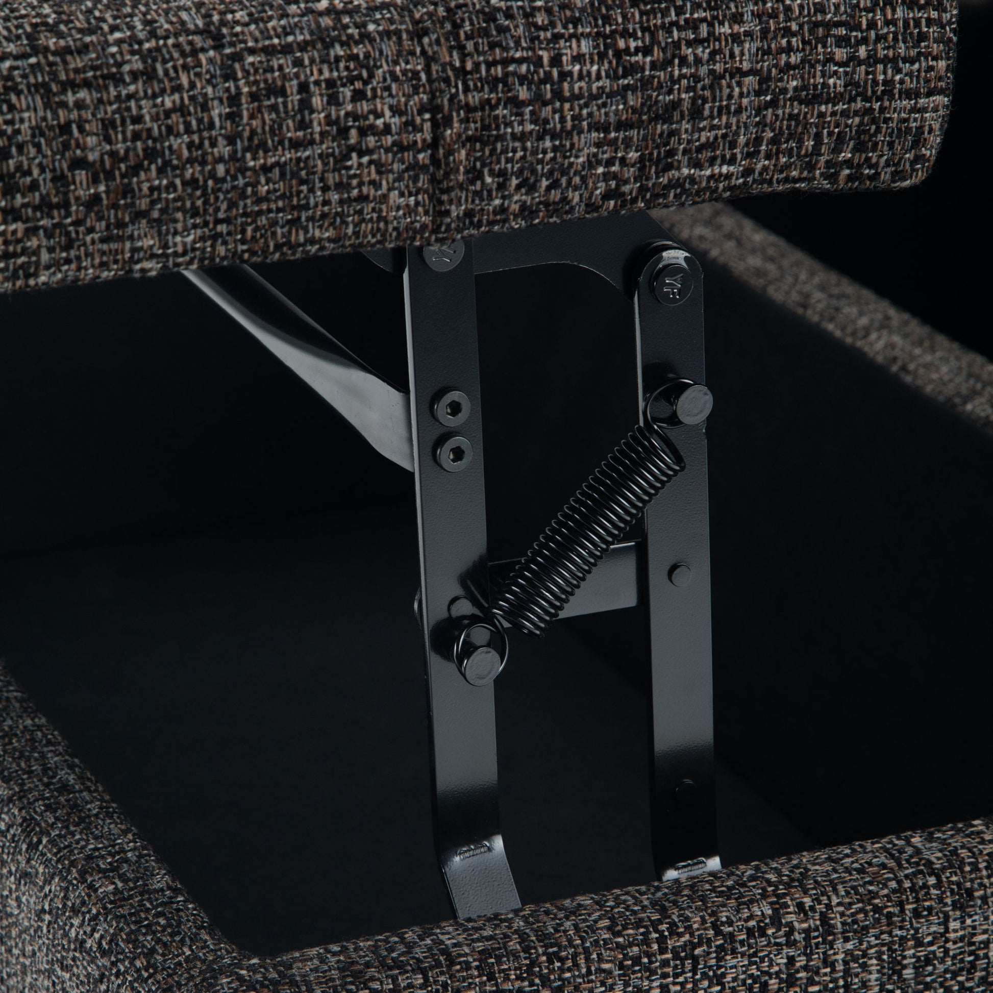 Close-up of a metal hinge and spring mechanism inside the Harrison Upholstered Coffee Table Storage Ottoman, with its fabric-covered lid partially open.