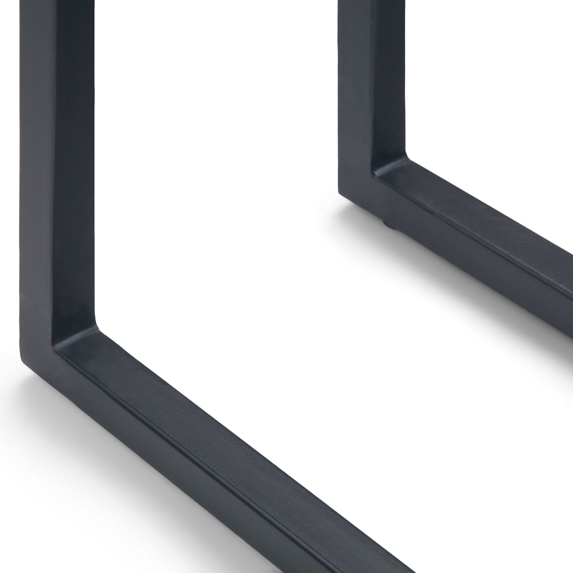 Close-up of the black metal legs of the Skyler - Handcrafted C Side Table on a white background. The legs form a right angle and cast subtle shadows on the surface.