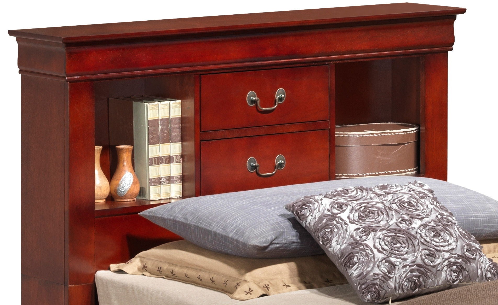 The Louis Phillipe Bookcase Storage Bed features a reddish-brown wooden headboard with shelves holding books, small vases, storage boxes, two central drawers, and bed pillows—including a floral one—arranged in front.