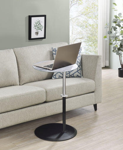 A modern living room features a light beige sofa with a geometric cushion, a laptop on the Orbit 15.5" End Table with Height Adjustable Marble Textured Top, a framed plant picture on the wall, and large windows filling the space with natural light.