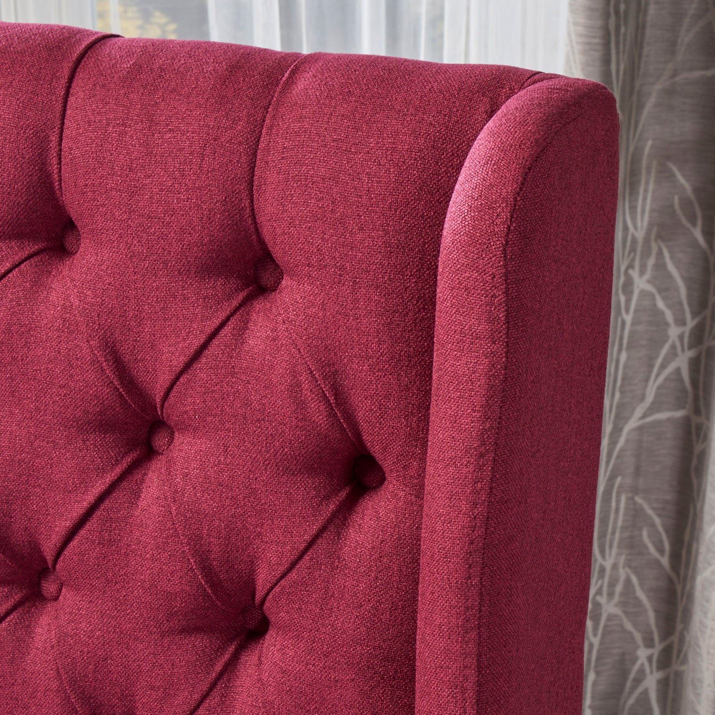 Close-up of the Sophisticated Tufted Dining Chair With High Back Design, upholstered in dark pink fabric with button details. Sheer white curtains and a gray tree branch-patterned curtain appear in the background.