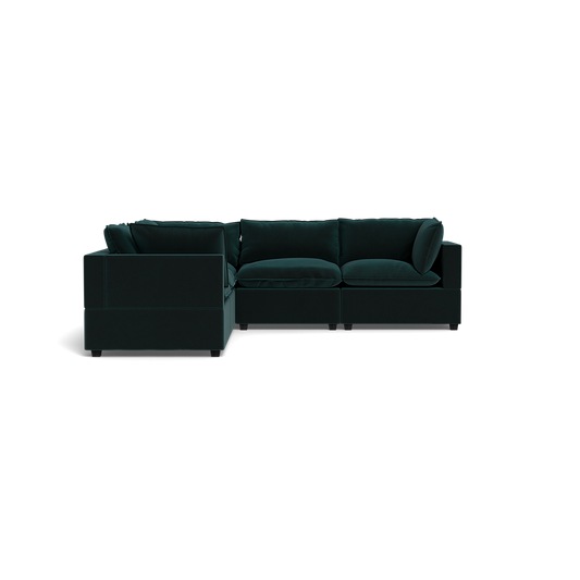 The Kova Pillow Cushion Corner Sectional, a dark green L-shaped sofa with plush cushions and wide armrests, is set against a solid black background.