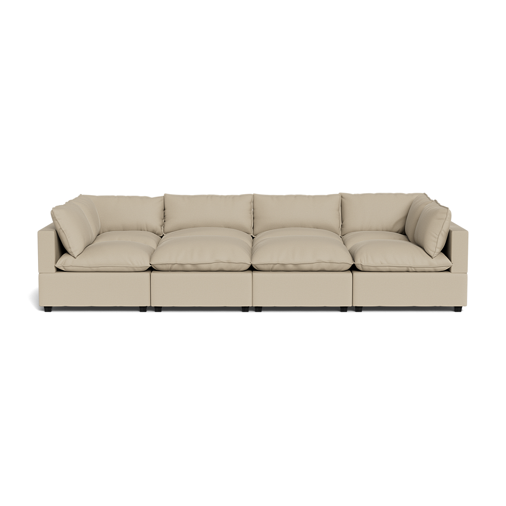 The Kova Pillow Cushion Grand Pit is a modern beige sectional sofa featuring plush seat and back cushions, four connected segments, and low square arms.