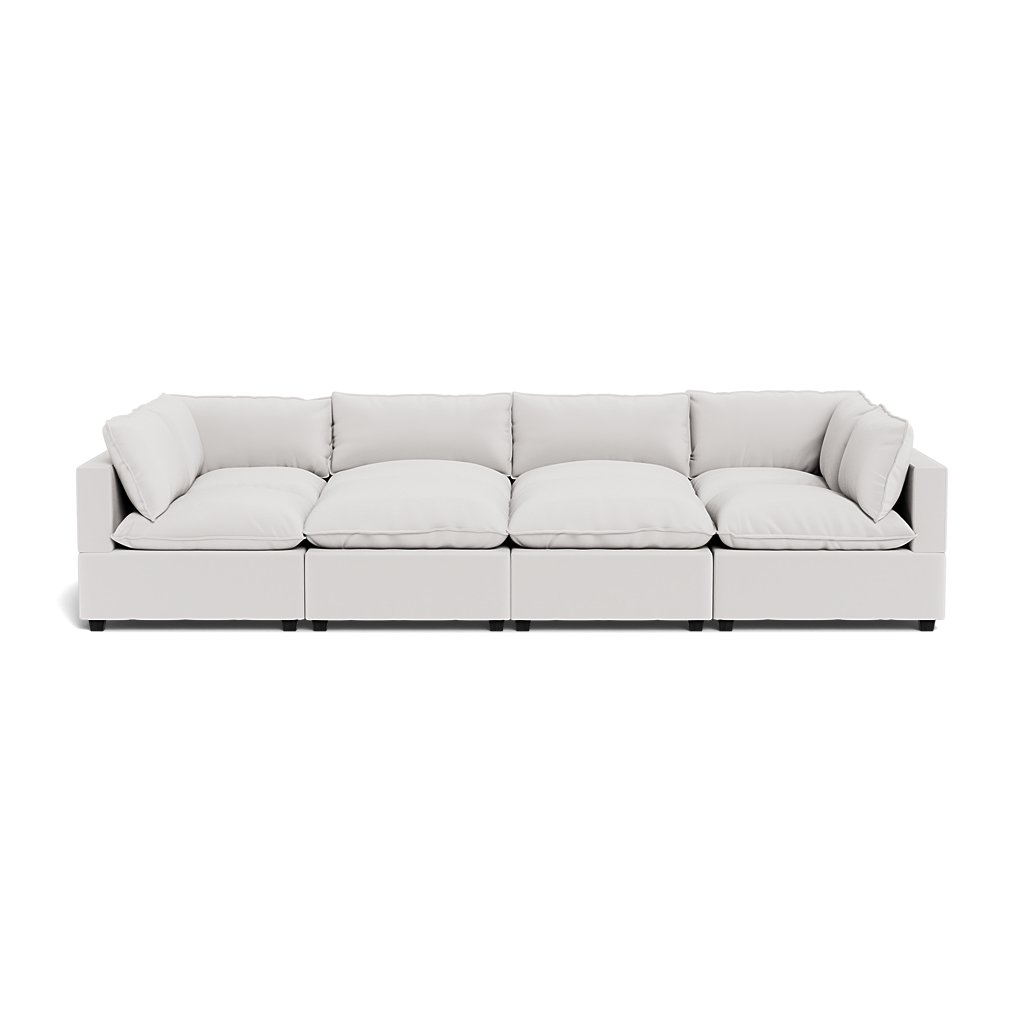 The Kova Pillow Cushion Grand Pit is a modern, light gray sectional sofa with four seats and plush seat and back cushions, shown from the front against a white background.