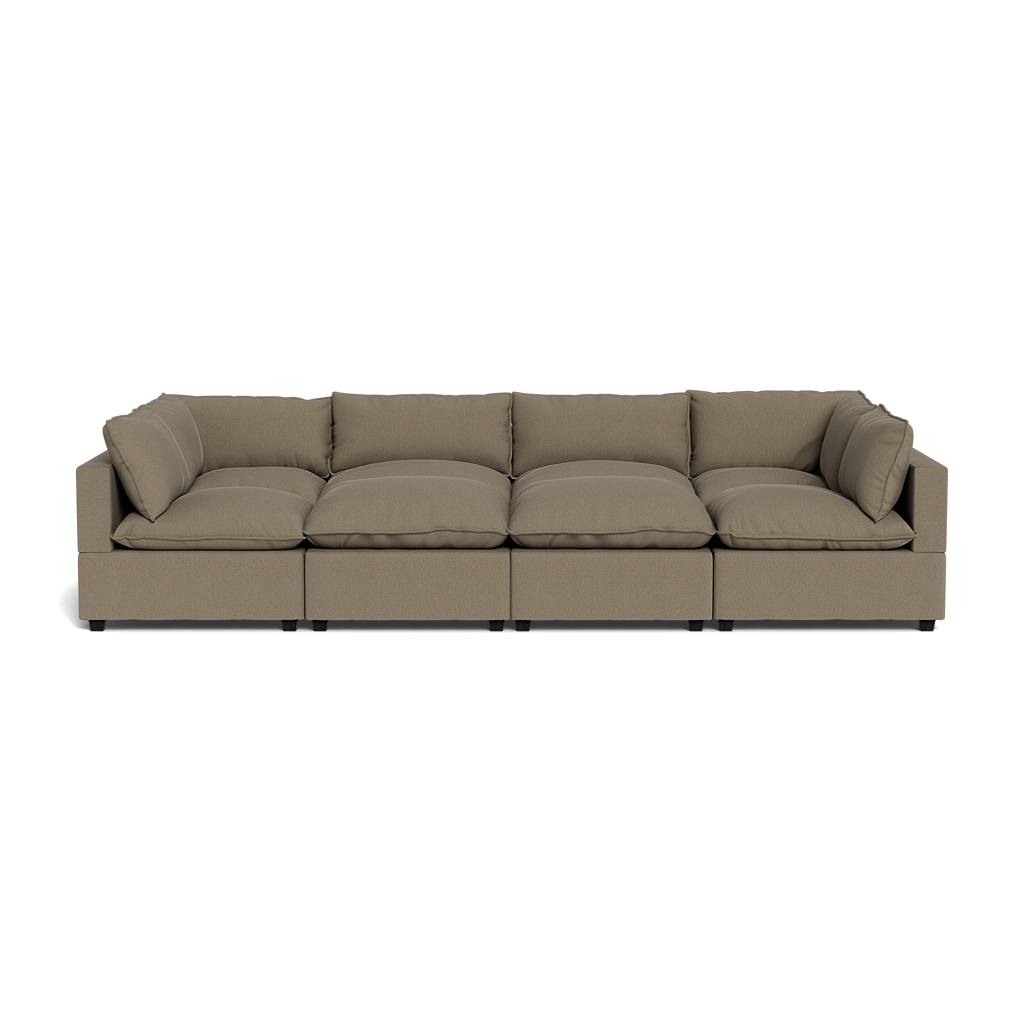 The Kova Pillow Cushion Grand Pit is a modern, long, light brown sectional sofa with four seat cushions and matching back cushions, shown from the front on a plain white background.