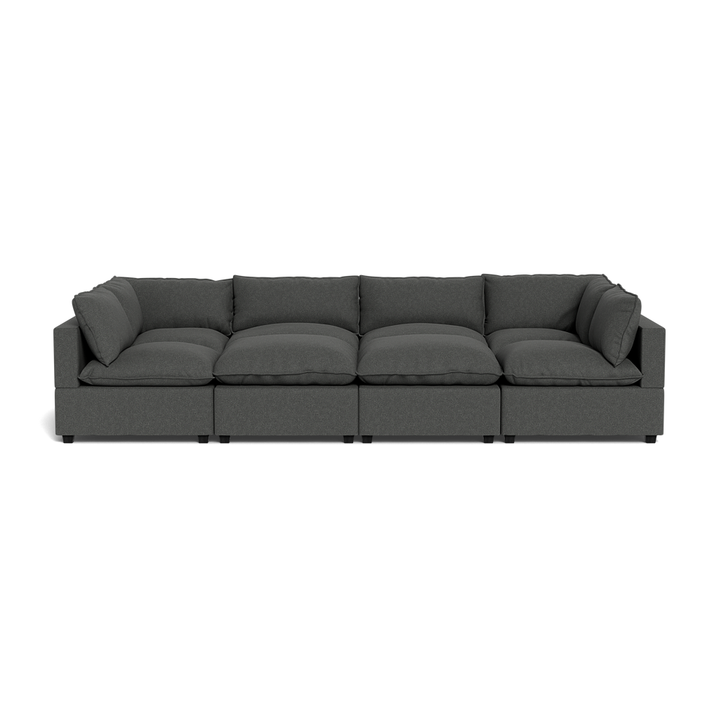 The Kova Pillow Cushion Grand Pit is a modern, dark gray sectional sofa with five seat and back cushions, shown from the front against a black background.