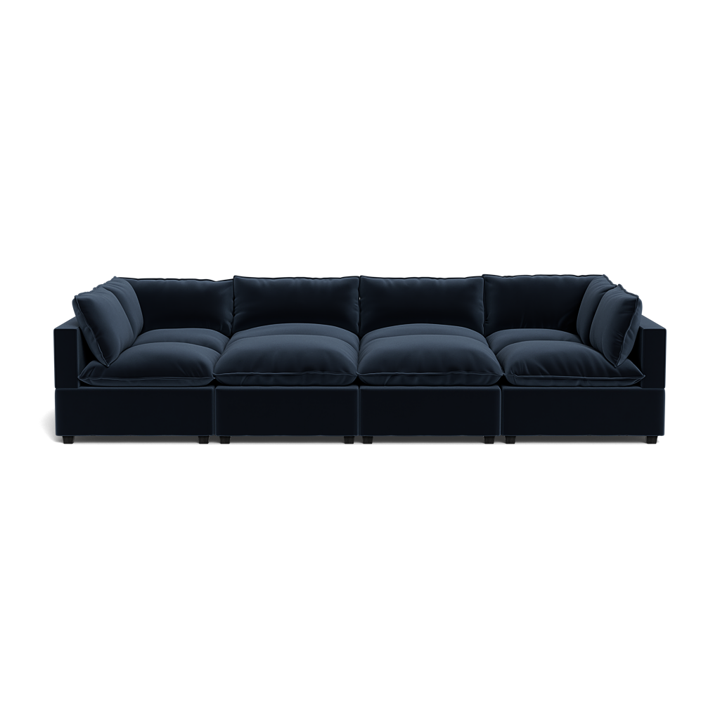 The Kova Pillow Cushion Grand Pit is a modern sectional sofa in deep navy blue, featuring plush cushions and wide armrests, photographed against a plain black background.