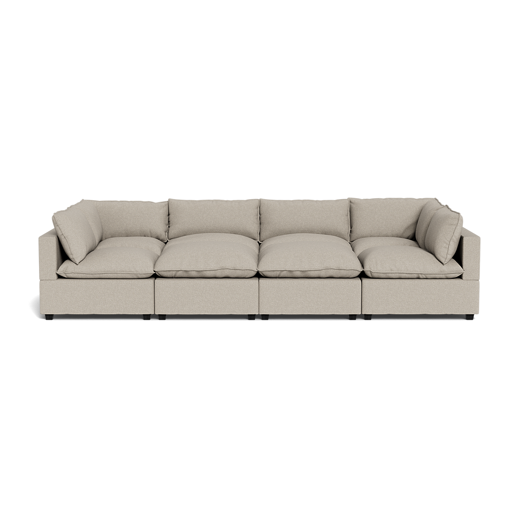 The Kova Pillow Cushion Grand Pit is a modern beige four-seat sectional sofa with plush cushions and armrests at each end, shown from the front against a plain background.