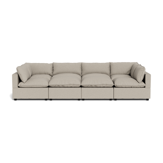 The Kova Pillow Cushion Grand Pit is a modern beige four-seat sectional sofa with plush cushions and armrests at each end, shown from the front against a plain background.