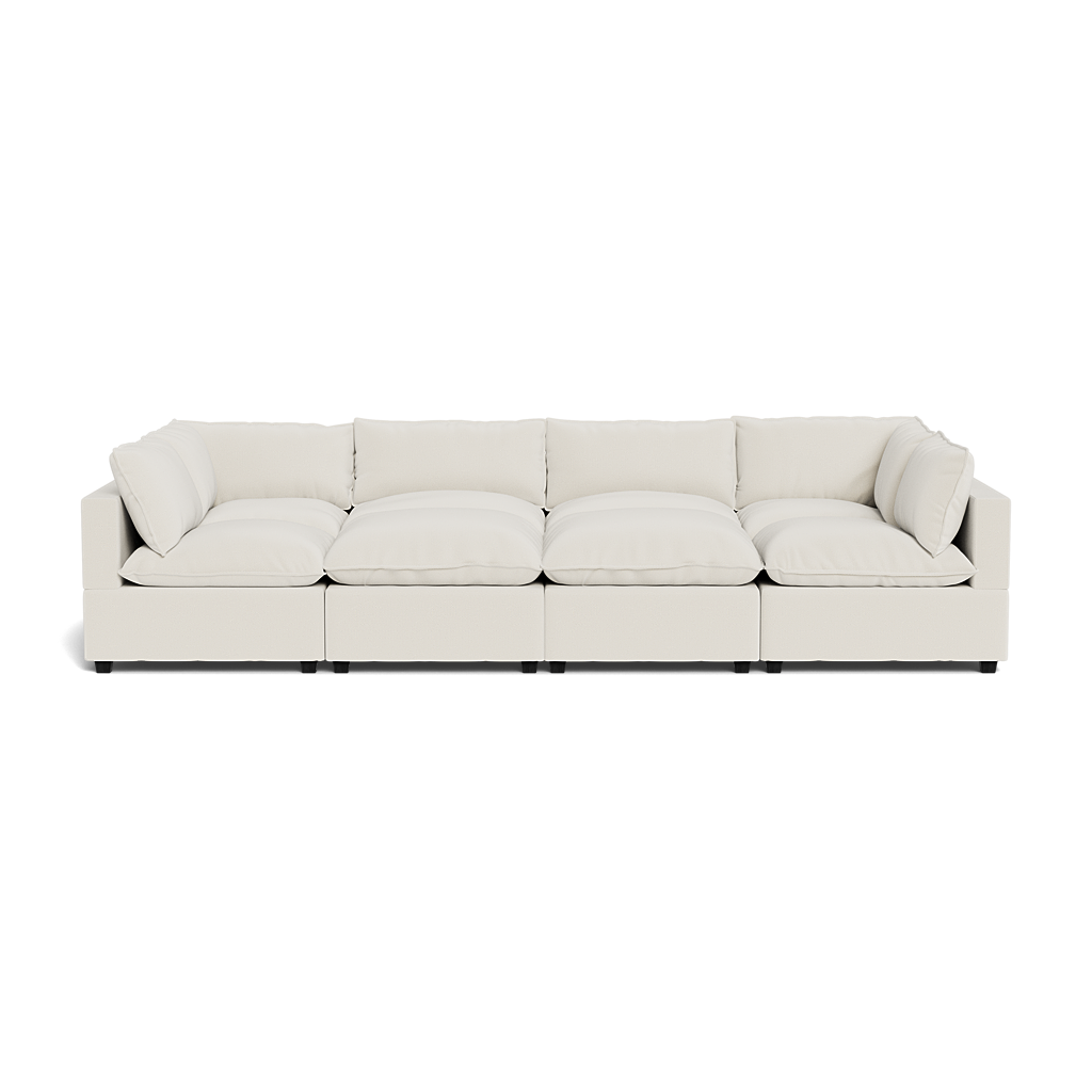 The Kova Pillow Cushion Grand Pit is a modern white sectional sofa with deep seats, plush cushions, and low square armrests, shown from the front against a plain background.