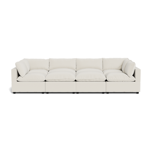 The Kova Pillow Cushion Grand Pit is a modern white sectional sofa with deep seats, plush cushions, and low square armrests, shown from the front against a plain background.