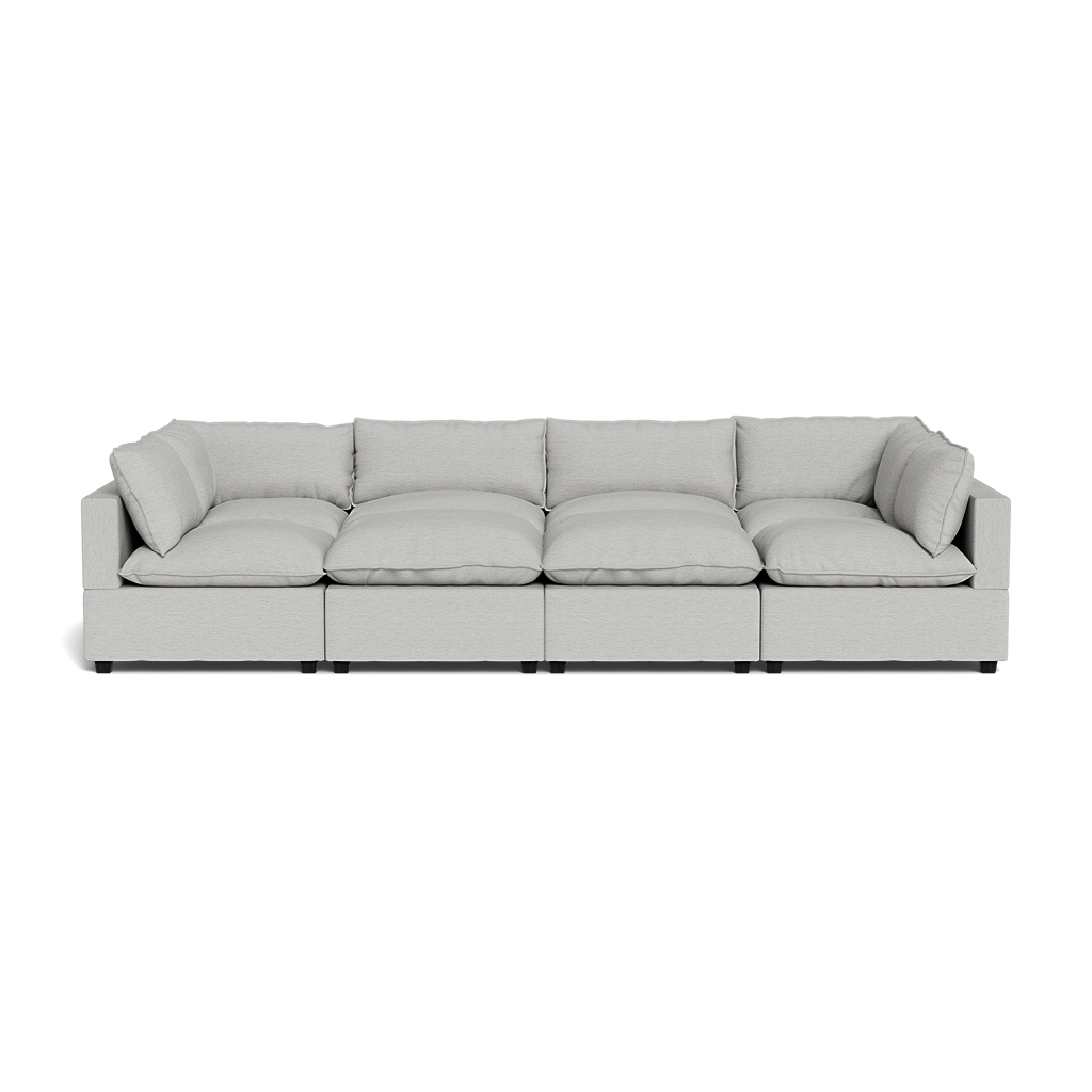 The Kova Pillow Cushion Grand Pit is a spacious, light gray modular sofa featuring four seat sections and six matching back and side cushions, shown from the front against a plain black background.