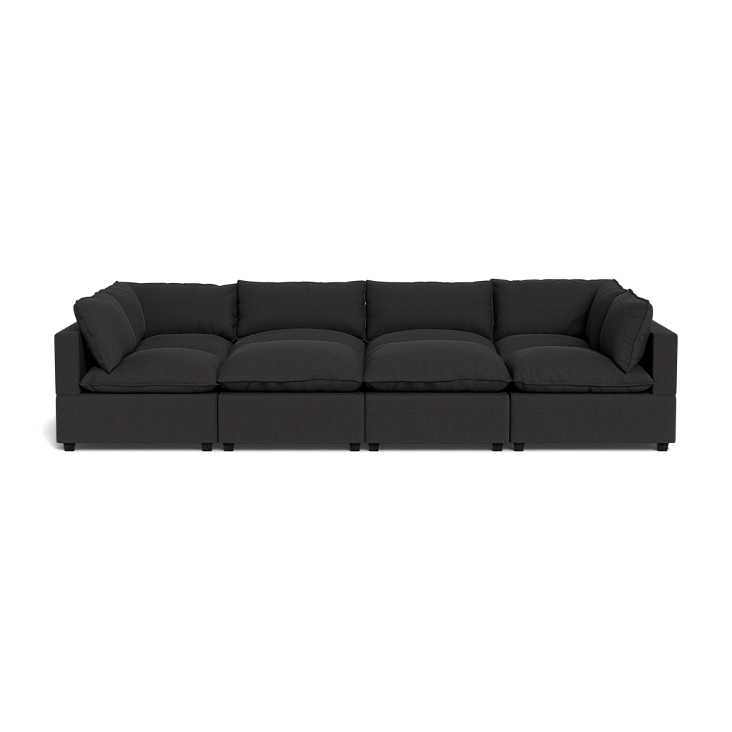 The Kova Pillow Cushion Grand Pit is a modern black modular sectional sofa with deep cushions and armrests on both ends, displayed against a plain black background.