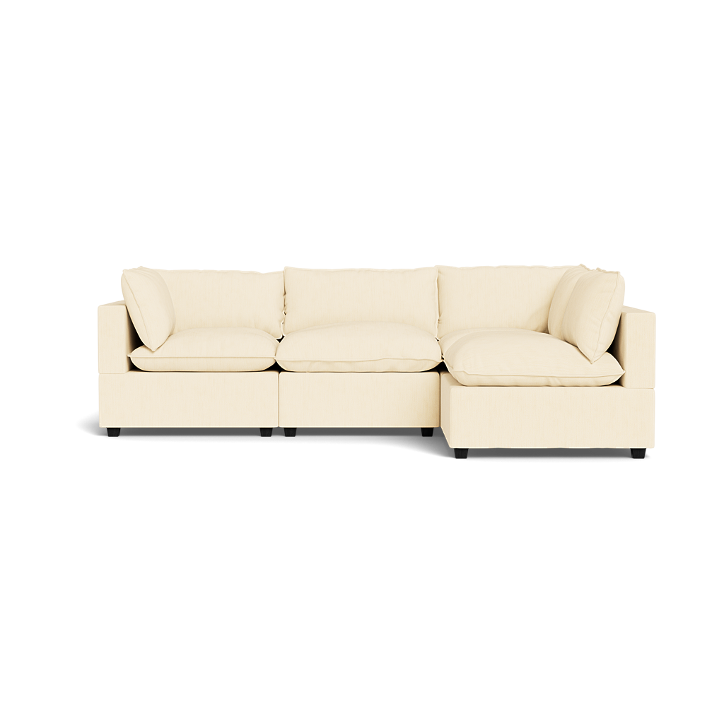 The Kova Pillow Cushion L-Shape is a modern beige sectional sofa with three seat cushions, a right-side chaise lounge, and four backrest cushions, shown isolated on a white background.