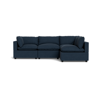 The Kova Pillow Cushion L-Shape is a modern dark blue sectional with three seat cushions, three back cushions, and two side cushions, shown against a plain black background.