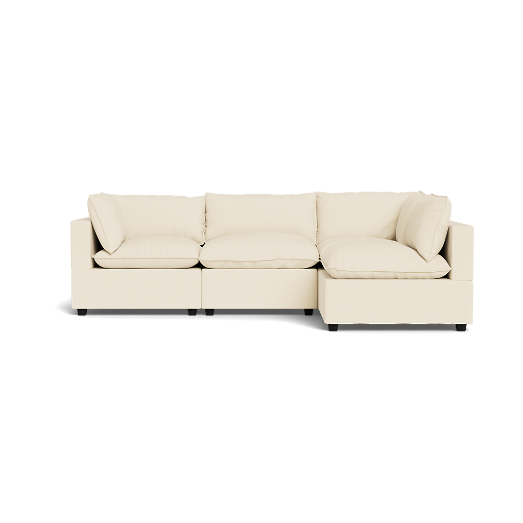 The Kova Pillow Cushion L-Shape is a modern, cream-colored sectional with three seat cushions, four back cushions, and armrests on both sides, shown from the front against a plain background.