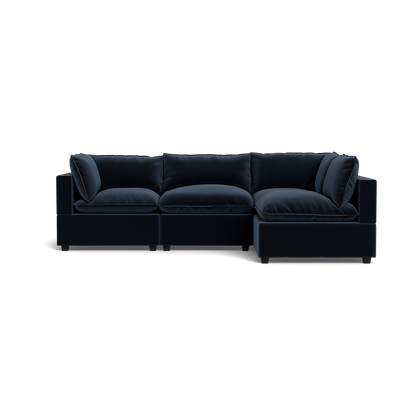 The Kova Pillow Cushion L-Shape is a modern dark navy blue sectional sofa with plush cushions and a right-side chaise, shown against a plain black background.